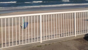 A beach view with a white metal railing in the foreground.