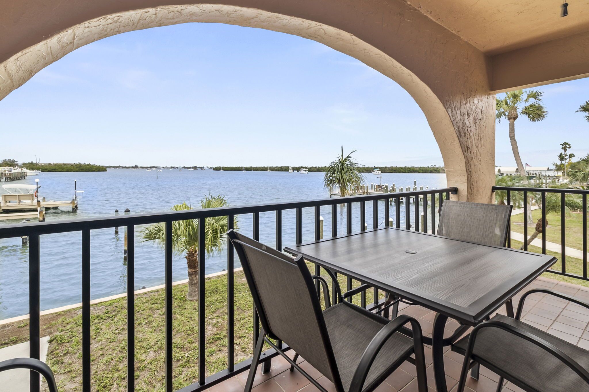 Ein Balkon mit Blick auf ruhiges Wasser, einem Holztisch und Stühlen.