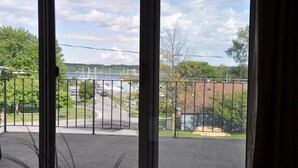 Vista de uma varanda com guarda-corpo de metal, uma estrada com veículos e uma ponte ao fundo.