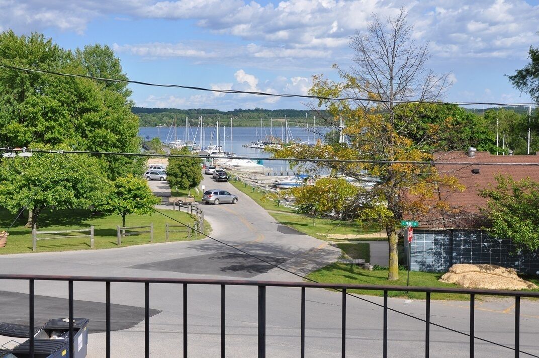 A marina with boats docked, a road leading to it, and a view of a lake.