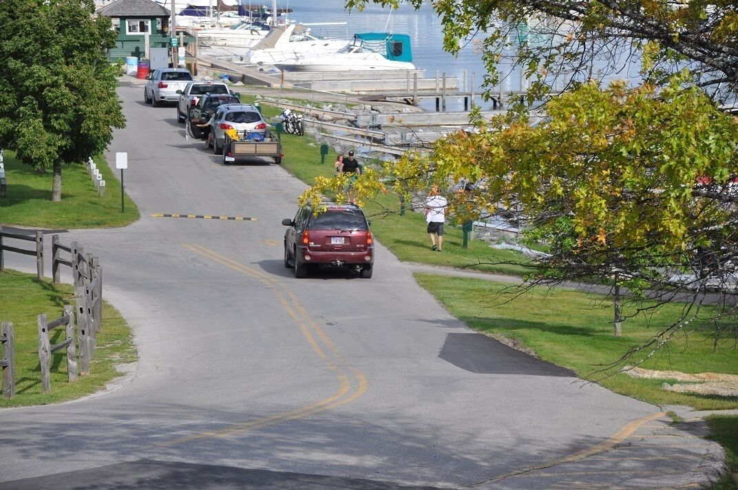 A marina with boats docked, a road leading to it, and a pedestrian path alongside.