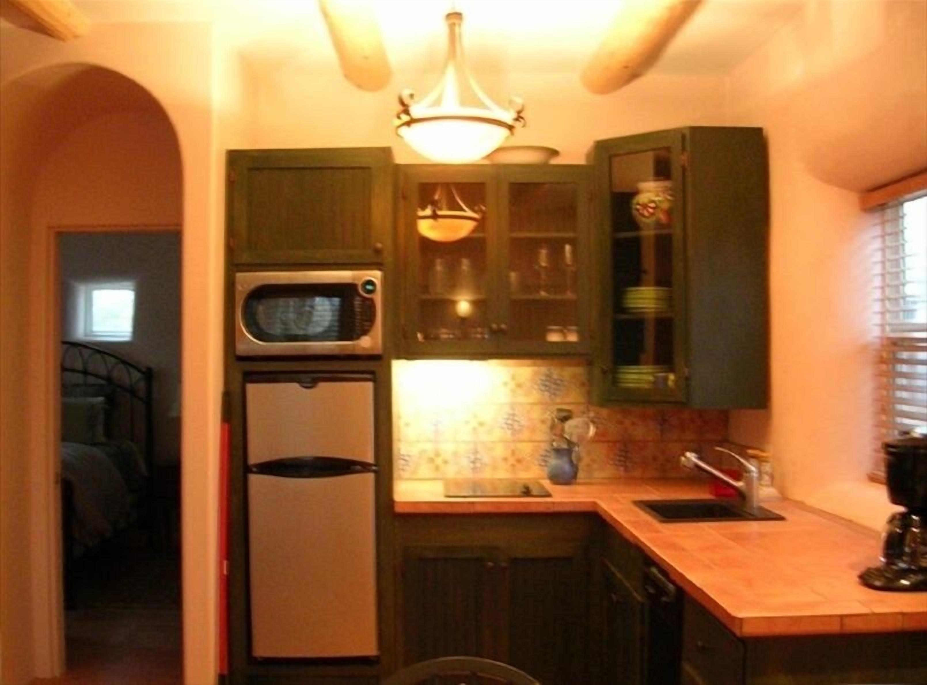 A compact kitchen with a microwave, refrigerator, and a small sink.