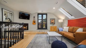 Un salon moderne avec une cheminée, un téléviseur, une guitare et un canapé.