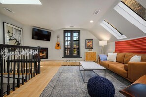 Un salon moderne avec une cheminée, un téléviseur, une guitare et un canapé.