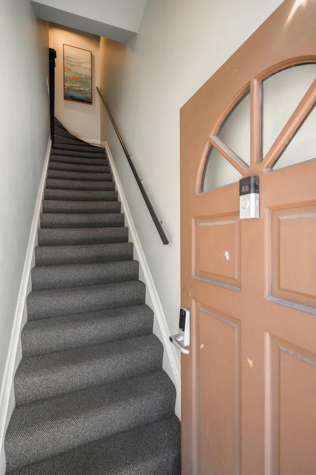 A staircase with carpeted steps leading to a door with a peephole.