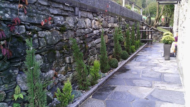 Un mur de pierres agrémenté de plantes et un chemin pavé de pierres.