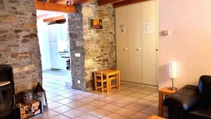 Un salon chaleureux avec un mur en pierre, une cheminée, une table en bois et un canapé.