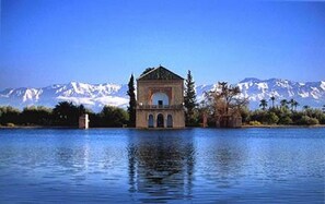 A building with a central dome and arched windows, surrounded by water and mountains in the background.