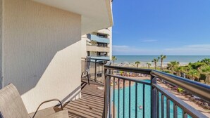 En balkon med udsigt over strand og pool.