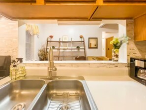 Una cucina con lavello in acciaio inossidabile, soffitto in legno e piano di lavoro bianco.
