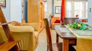 Un salon chaleureux avec une table à manger en bois, des fauteuils beiges et un rideau rouge.