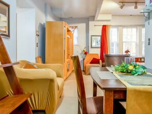Un soggiorno accogliente con un tavolo da pranzo in legno, poltrone beige e una tenda rossa.