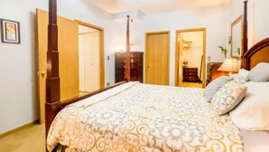 Une chambre à coucher avec un grand lit, un ventilateur de plafond et des portes en bois.