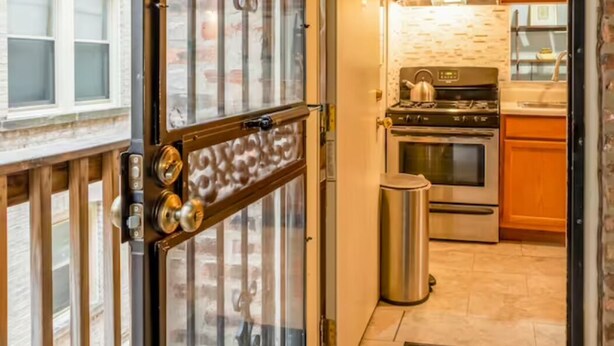 Une cuisine avec des meubles en bois, une cuisinière en acier inoxydable et une poubelle.