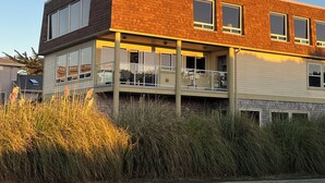A modern two-story building with a flat roof, large windows, and a balcony.