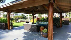 Un espacio de estar al aire libre con techo, muebles de mimbre y plantas en macetas.
