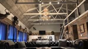 Un salon spacieux avec un grand canapé d’angle, une table basse en bois et un lustre.