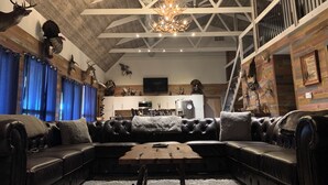 Un salon moderne avec un canapé d’angle, une table basse en bois et un lustre.