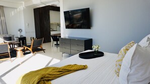 Ein modernes Hotelzimmer mit einem großen Bett, einem Schreibtisch, einem Sessel und einem an der Wand befestigten Fernseher.