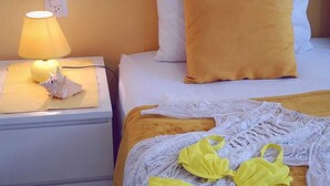 Una habitación de hotel con una cama, una mesita de noche con lámpara y un par de sostenes amarillos sobre la cama.