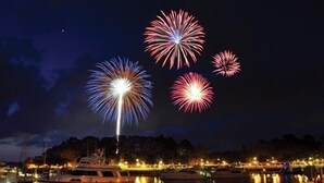 A marina at night with boats docked and fireworks in the sky.