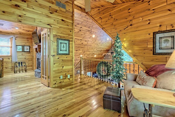 Een gezellig houten blokhut interieur met een trap, een kerstboom en een comfortabele zithoek.