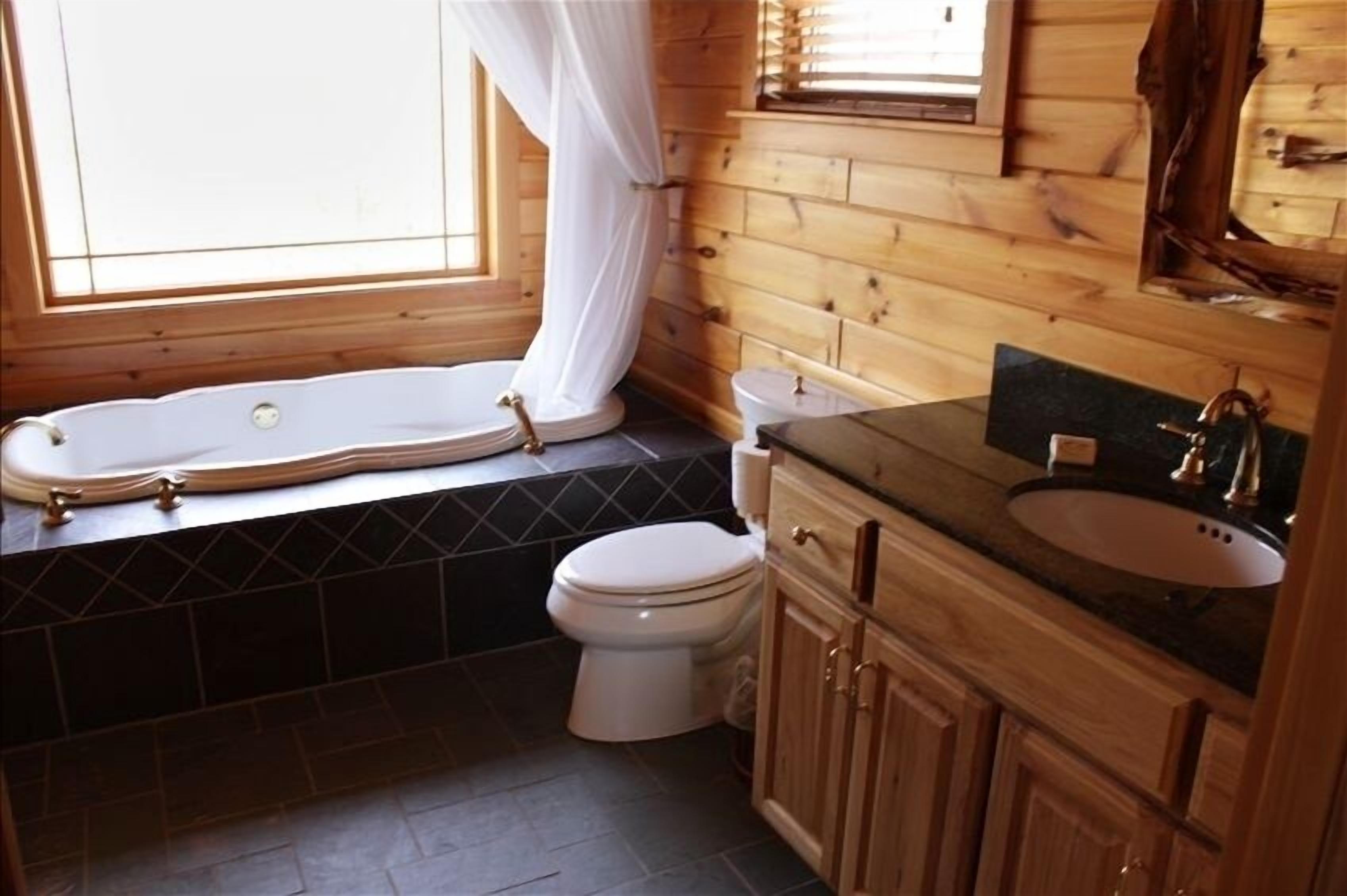 A bathroom with a bathtub, toilet, and wooden vanity.