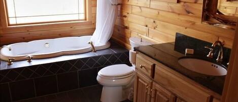 A bathroom with a bathtub, toilet, and wooden vanity.