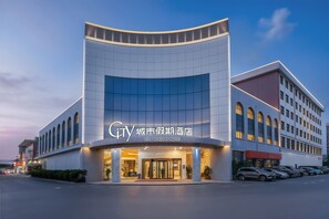 A modern hotel with a curved facade, large windows, and a well-lit entrance. - City Holiday Hotel Guangzhou Baiyun Airport-Free Shuttles During the 140th Canton Fair (Guangzhou)