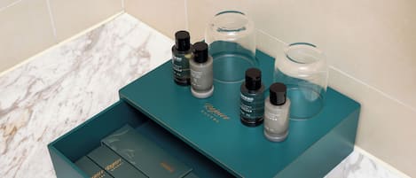 A teal box with skincare products and a glass container on a marble countertop.