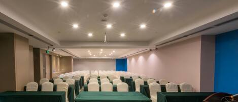 A conference room with rows of chairs, tables, and a podium.