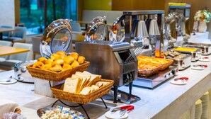 Ein reichhaltiges Buffet mit Brot, Gebäck und einer Kaffeestation.