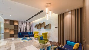 Eine moderne Lobby mit einem blauen Sofa, einem gelben Sessel und einem kleinen Tisch mit einer Lampe.