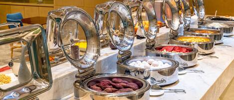 A buffet with various food items in metal containers, including eggs, vegetables, and other dishes.