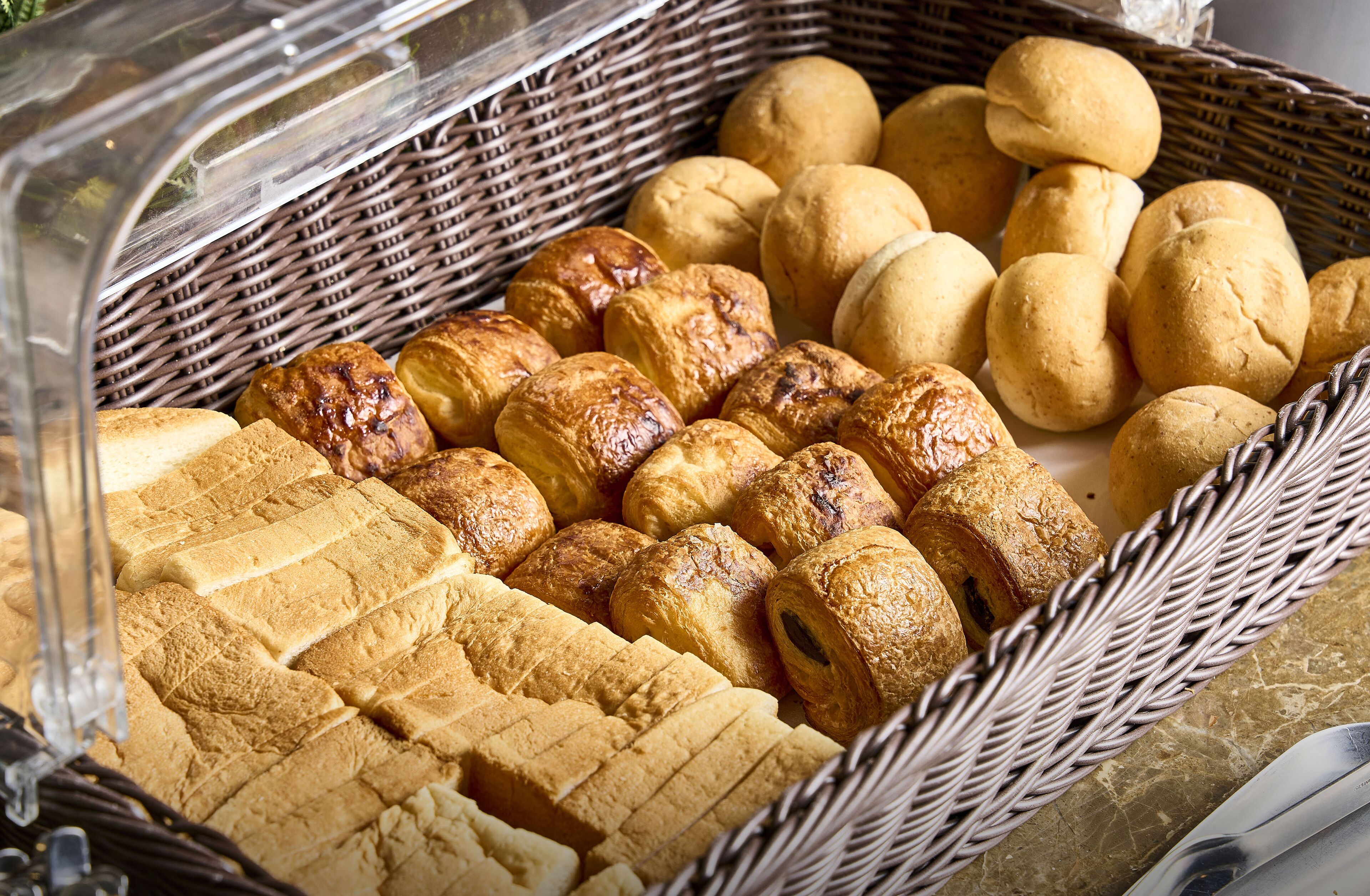 A basket filled with various types of bread, including baguettes and rolls.