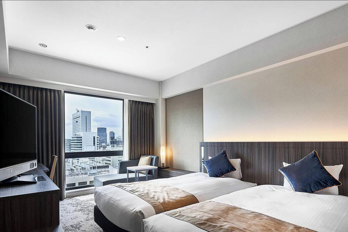 Habitación de hotel con una cama grande, televisión, escritorio y vistas a la ciudad.