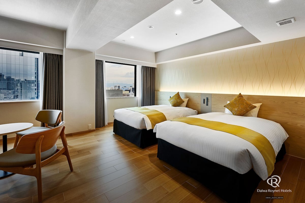 Una habitación de hotel con dos camas, un comedor y vistas a la ciudad.