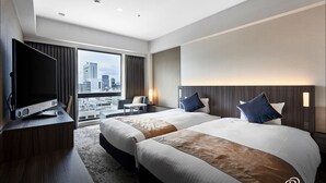 A hotel room with two beds, a TV, a desk, and a view of the city. - DEL style Osaka - Shinsaibashi by Daiwa Roynet Hotel (Osaka)