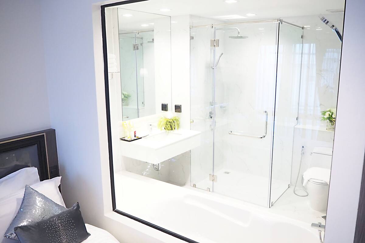 A modern bathroom with a glass-enclosed shower, a white sink, and a toilet.