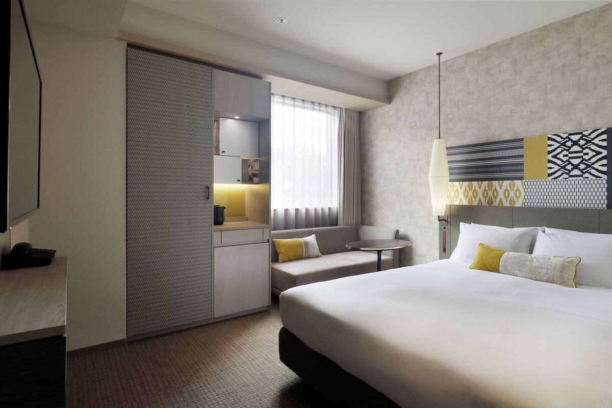 Ein Hotelzimmer mit einem großen Bett, einem Schreibtisch, einer Couch und einem kleinen Tisch.