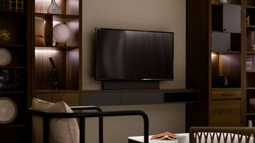 A modern living room with a flat-screen TV mounted on the wall, a sofa, a coffee table, and built-in wooden shelving with decorative items.