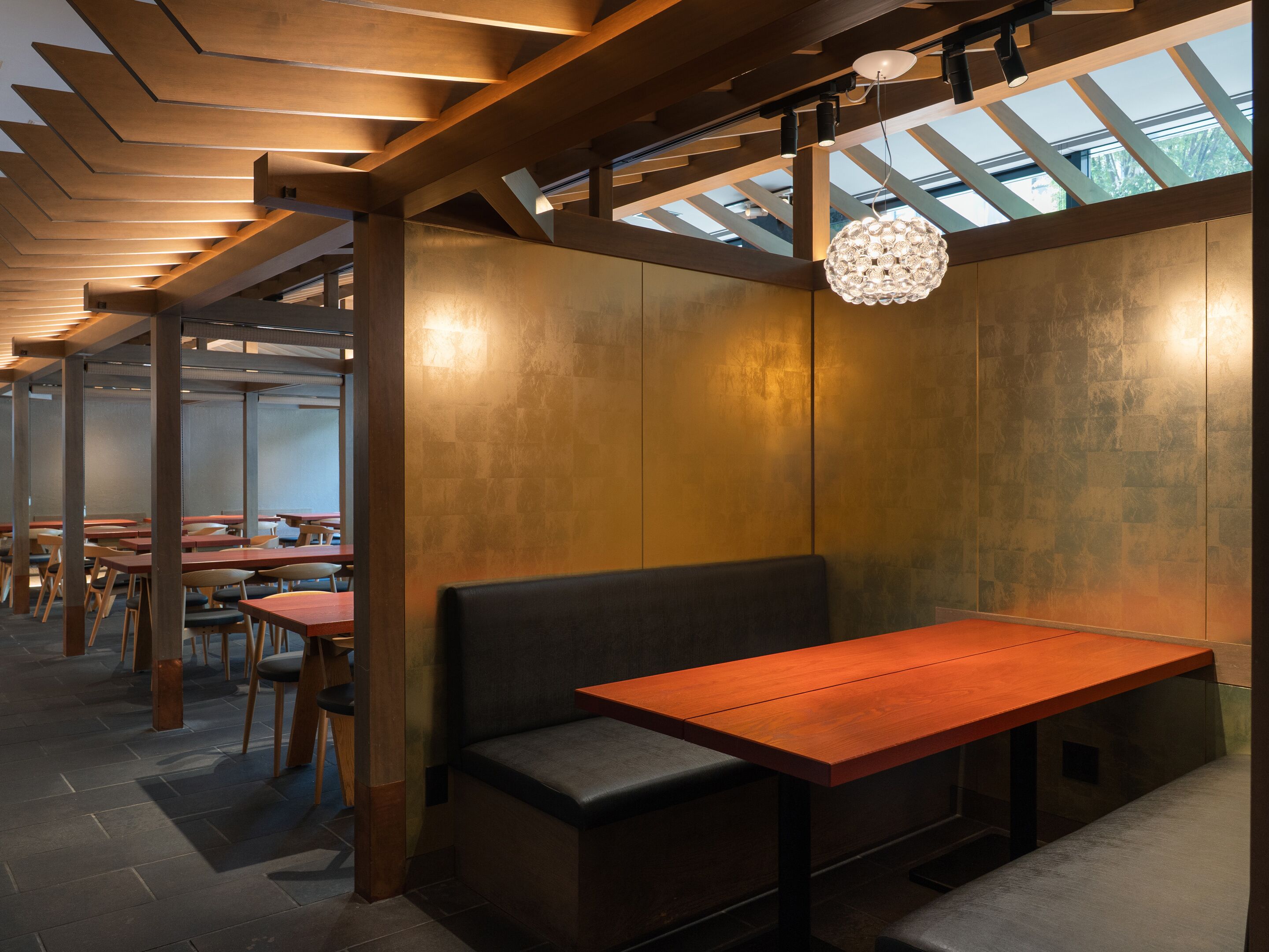 A modern interior with wooden beams, a bench, tables, and a unique chandelier.