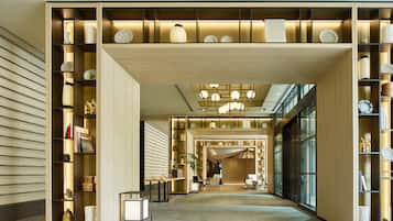 A modern hotel lobby with a central seating area, a large window, and a decorative ceiling.