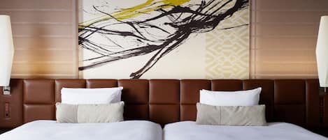 Habitación de hotel con un cuadro abstracto grande en la pared, dos camas con ropa blanca y un cabecero marrón.
