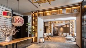 Um lobby moderno de hotel com uma mesa de recepção de madeira, área de estar e vista para os quartos de hóspedes.