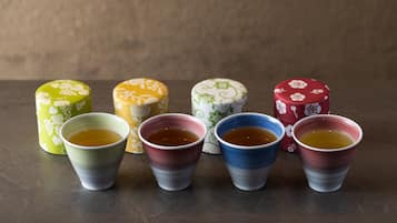 Six cups of tea and four cylindrical containers on a table.
