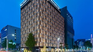 Um hotel moderno com fachada em estilo geométrico, vários andares e sinalização iluminada.