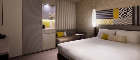 A hotel room with a large bed, a seating area, a small table, and a wardrobe.