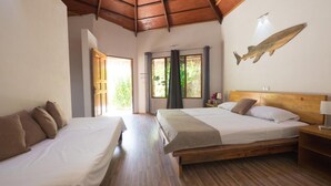 A room with two beds, wooden flooring, a wooden ceiling, a window with curtains, and a wall-mounted fish decoration.