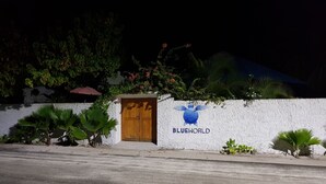 A building with a wooden door and a wall with the text "BLUEWORLD".